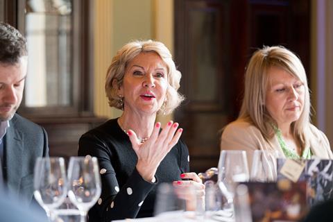 Photograph focused on Carpenters Group director Donna Scully engaging in a discussion with an attendee sitting opposite her at the roundtable. She wears a black top and bright pink nail varnish.